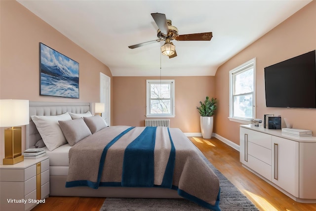 bedroom featuring radiator, baseboards, multiple windows, and light wood-type flooring