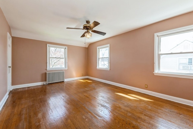 spare room featuring radiator, hardwood / wood-style floors, a ceiling fan, and baseboards
