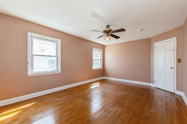 unfurnished room with wood finished floors, a ceiling fan, and baseboards