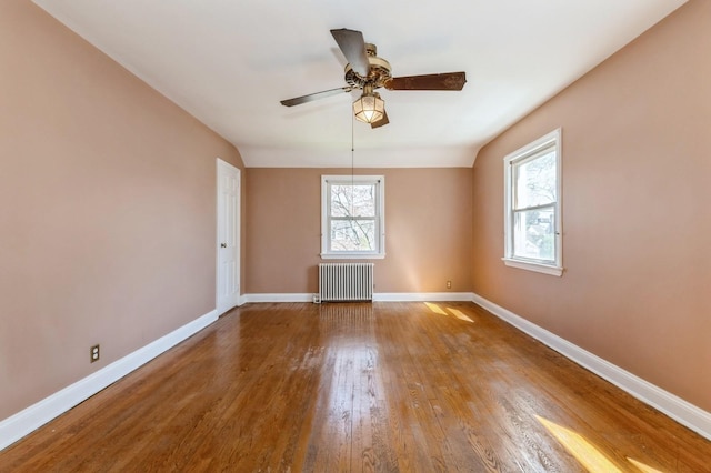 unfurnished room featuring radiator, baseboards, wood finished floors, and ceiling fan
