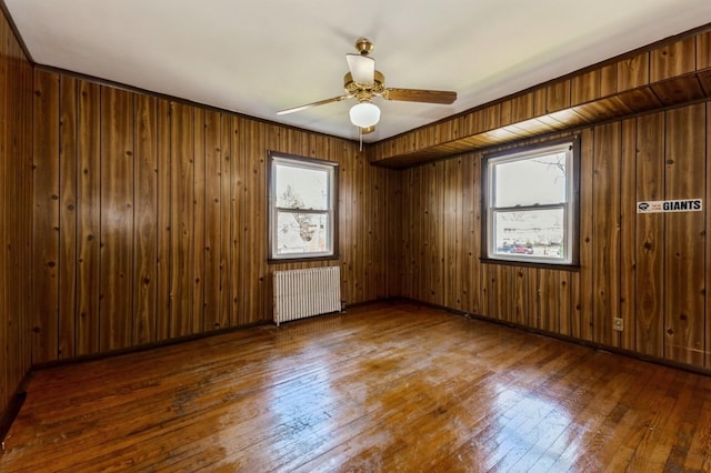 empty room featuring wood-type flooring, radiator heating unit, and ceiling fan