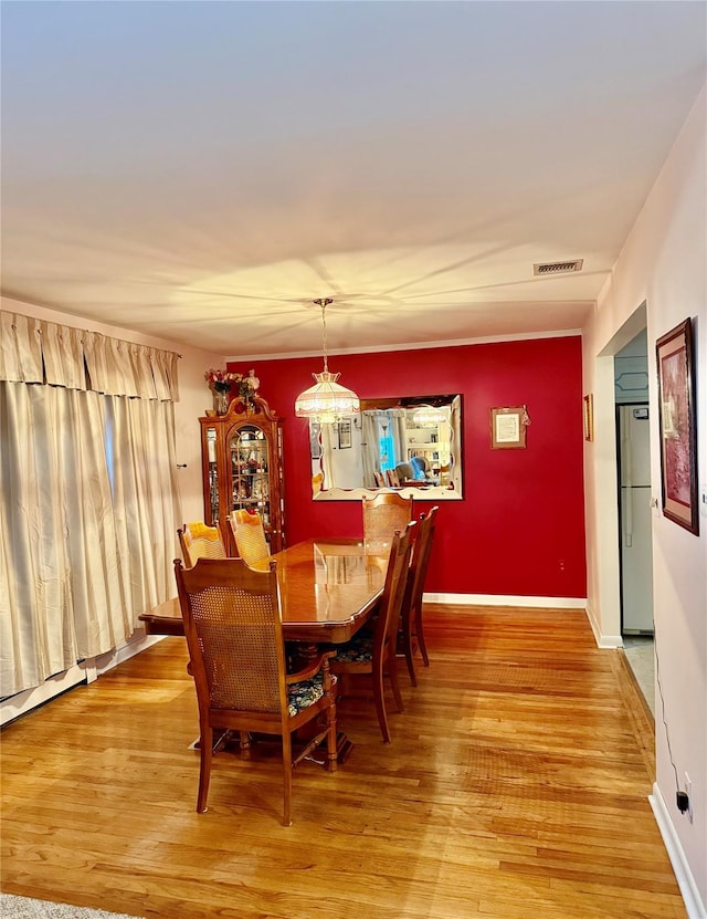 dining room featuring light wood-style floors, visible vents, and baseboards