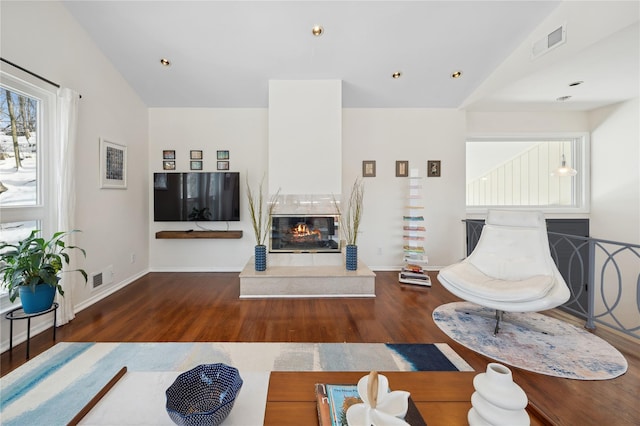 living room with a fireplace, visible vents, and dark wood-type flooring