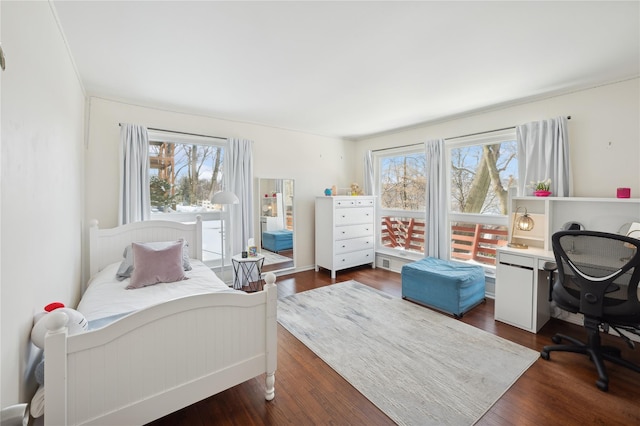 bedroom with dark wood-style floors and multiple windows