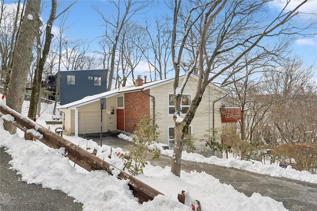 view of front of house with a garage, brick siding, and a chimney