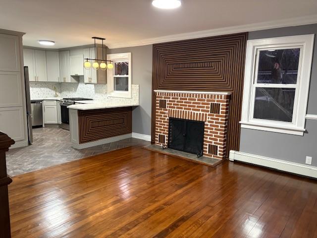 interior space with baseboard heating, ornamental molding, dark wood-type flooring, and a brick fireplace