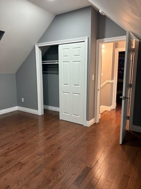 unfurnished bedroom with lofted ceiling, dark hardwood / wood-style flooring, and a closet