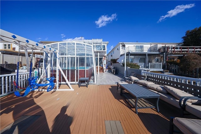 wooden terrace featuring a pool and glass enclosure