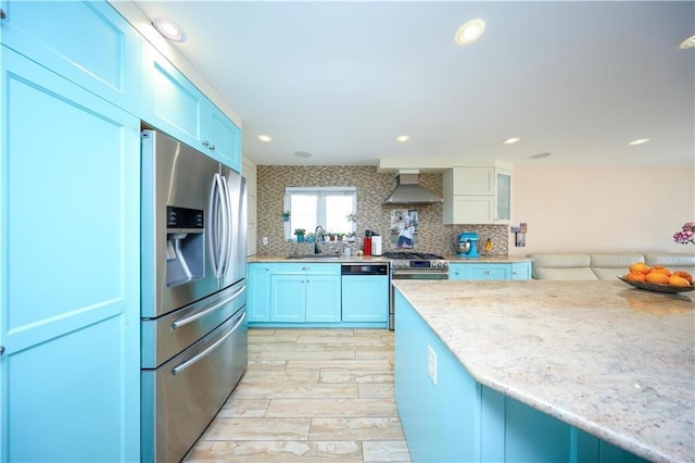 kitchen with stainless steel appliances, sink, wall chimney range hood, and decorative backsplash