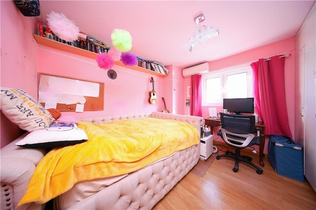 bedroom with light hardwood / wood-style flooring and a wall unit AC