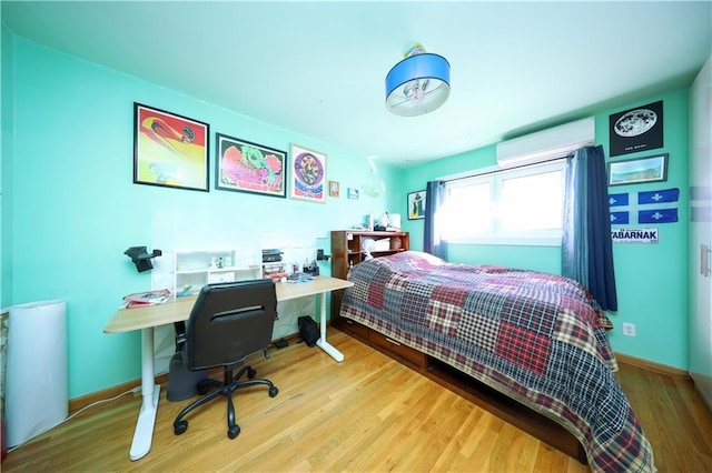 bedroom with light wood-type flooring and an AC wall unit