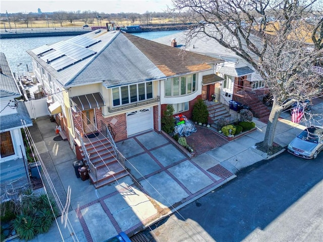 view of front of property featuring a water view, a garage, and solar panels