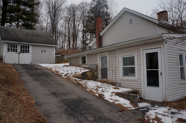 view of snow covered exterior featuring an outbuilding