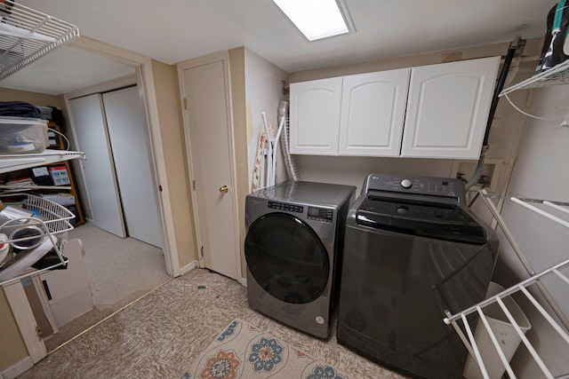 laundry room featuring separate washer and dryer, light carpet, and cabinets
