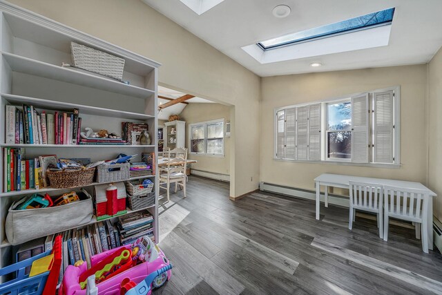 game room with baseboard heating, wood-type flooring, and lofted ceiling with skylight