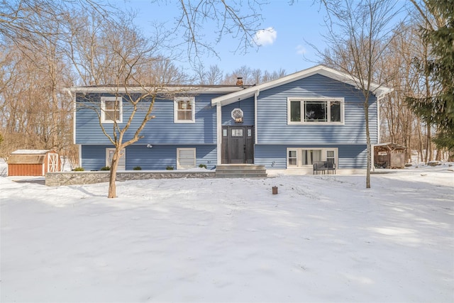 split foyer home featuring entry steps, a shed, a chimney, and an outdoor structure