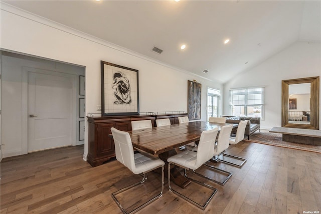 dining room with high vaulted ceiling, ornamental molding, and hardwood / wood-style floors