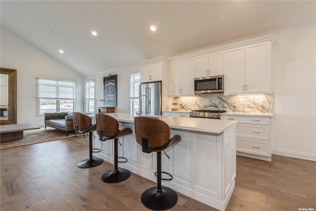 kitchen featuring a kitchen bar, a center island with sink, white cabinets, and appliances with stainless steel finishes