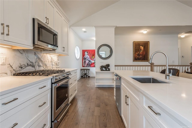 kitchen featuring sink, appliances with stainless steel finishes, dark hardwood / wood-style floors, white cabinets, and vaulted ceiling