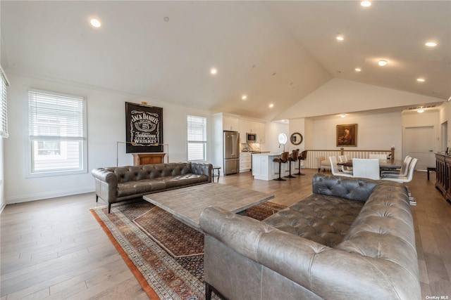 living room featuring high vaulted ceiling and light hardwood / wood-style floors