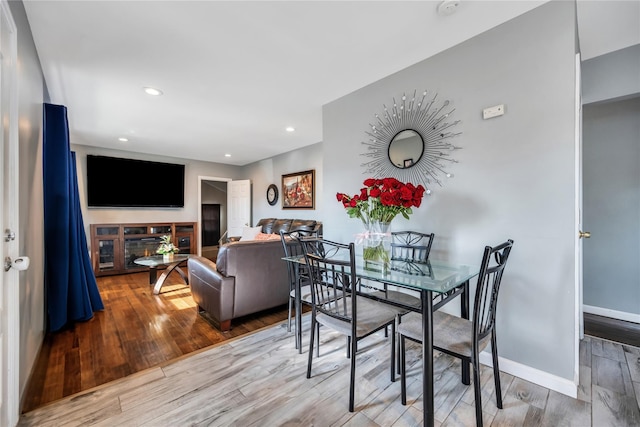 dining area with recessed lighting, baseboards, wood finished floors, and a glass covered fireplace