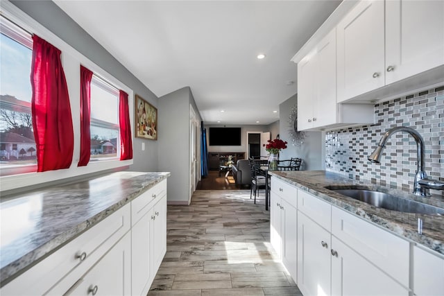 kitchen featuring tasteful backsplash, light wood-style flooring, white cabinetry, a sink, and recessed lighting