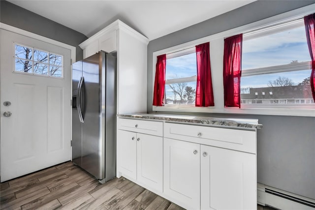 kitchen with white cabinets, light wood-style floors, a baseboard radiator, and stainless steel refrigerator with ice dispenser