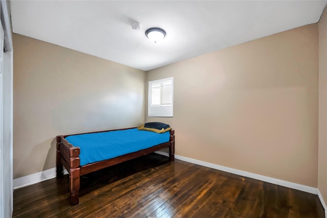 bedroom with dark wood-type flooring and baseboards