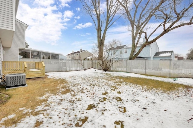 yard layered in snow featuring central air condition unit and a deck