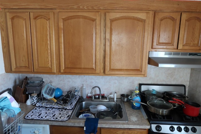 11551 209th St, Cambria Heights, NY 11411 - kitchen featuring decorative backsplash, light countertops, gas stove, under cabinet range hood, and a sink