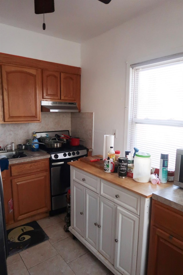 11551 209th St, Cambria Heights, NY 11411 - kitchen featuring light tile patterned flooring, backsplash, a sink, stainless steel range with gas stovetop, and under cabinet range hood