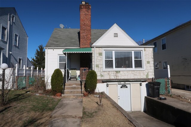 11551 209th St, Cambria Heights, NY 11411 - view of front of property with stone siding, a chimney, and fence