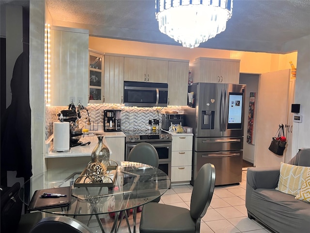 200-21 Hollis Ave, Saint Albans, NY 11412 - kitchen with light tile patterned floors, backsplash, stainless steel appliances, a notable chandelier, and a textured ceiling