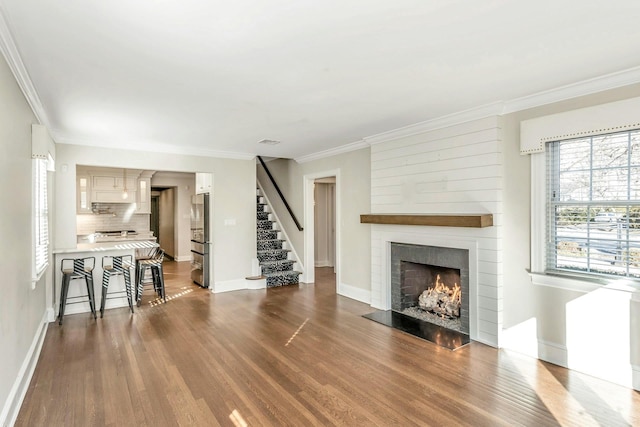 unfurnished living room featuring a large fireplace, dark wood-type flooring, and crown molding