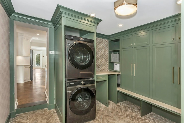 laundry area with stacked washer / drying machine and crown molding