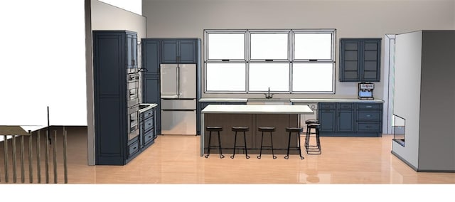 kitchen featuring a breakfast bar, a sink, a center island, freestanding refrigerator, and light countertops