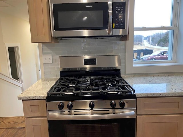 kitchen with light stone counters, appliances with stainless steel finishes, and backsplash