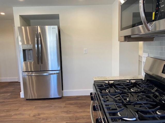 kitchen with appliances with stainless steel finishes, dark wood-type flooring, and decorative backsplash