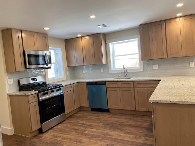 kitchen with stainless steel appliances, sink, dark wood-type flooring, and light stone counters