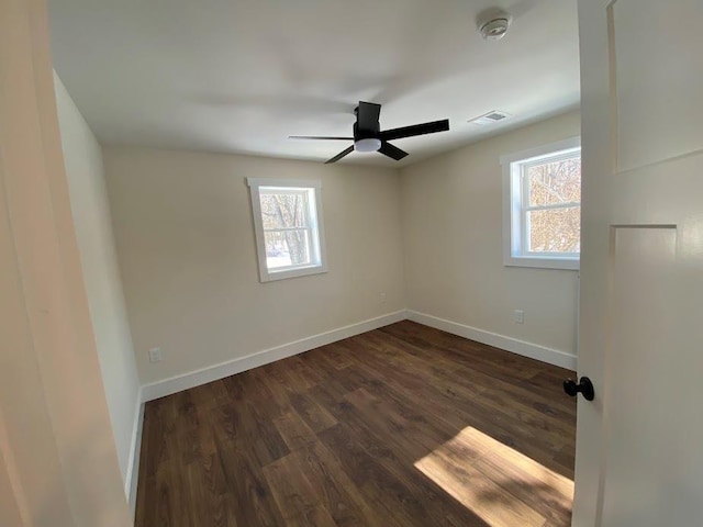 spare room featuring dark hardwood / wood-style flooring, ceiling fan, and a healthy amount of sunlight