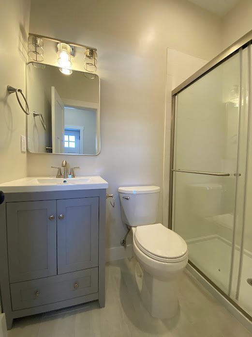 bathroom featuring vanity, a shower with shower door, and toilet