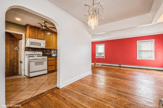 kitchen with light wood-type flooring, white appliances, tasteful backsplash, crown molding, and pendant lighting