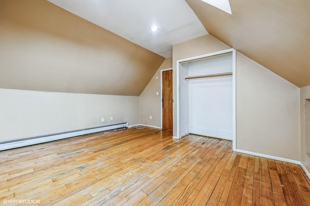 bonus room featuring a baseboard heating unit, lofted ceiling with skylight, and light hardwood / wood-style floors