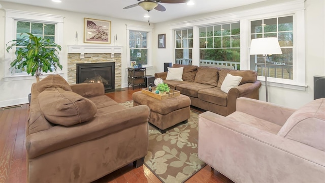 living room featuring ceiling fan, a stone fireplace, and light hardwood / wood-style floors