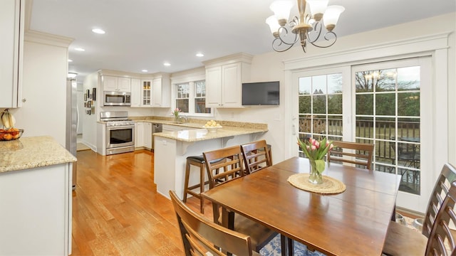 dining area featuring a notable chandelier, sink, and light wood-type flooring