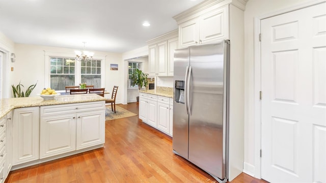 kitchen featuring pendant lighting, white cabinets, light hardwood / wood-style floors, and stainless steel fridge with ice dispenser