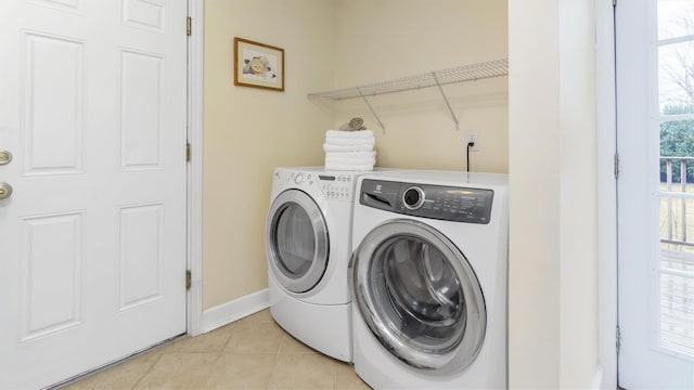 laundry area with separate washer and dryer and light tile patterned floors