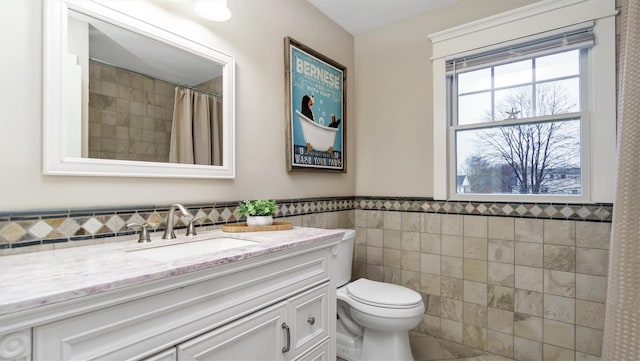 bathroom with tile walls, vanity, a shower with curtain, and toilet