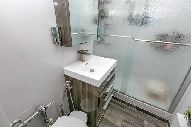 bathroom featuring a shower with door, vanity, and toilet