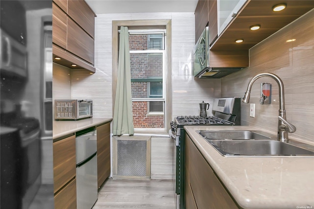 kitchen featuring tasteful backsplash, appliances with stainless steel finishes, sink, and light wood-type flooring